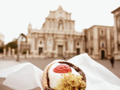 Sicilian pastry called Cannoli eating in front of cathedral in Catania